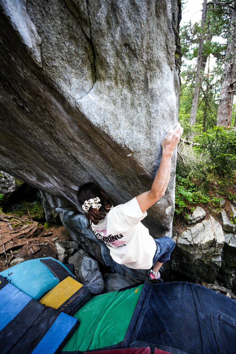 Girl climbing a rock face with greenery in the background